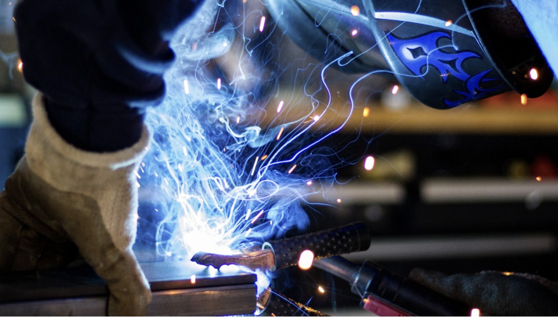 Welder with mask on and blue light and sparks