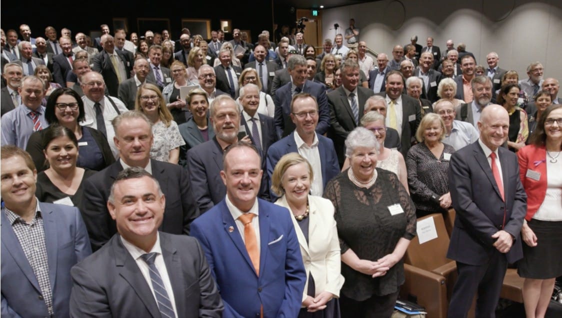 Large group of politicians standing and smiling in conference room