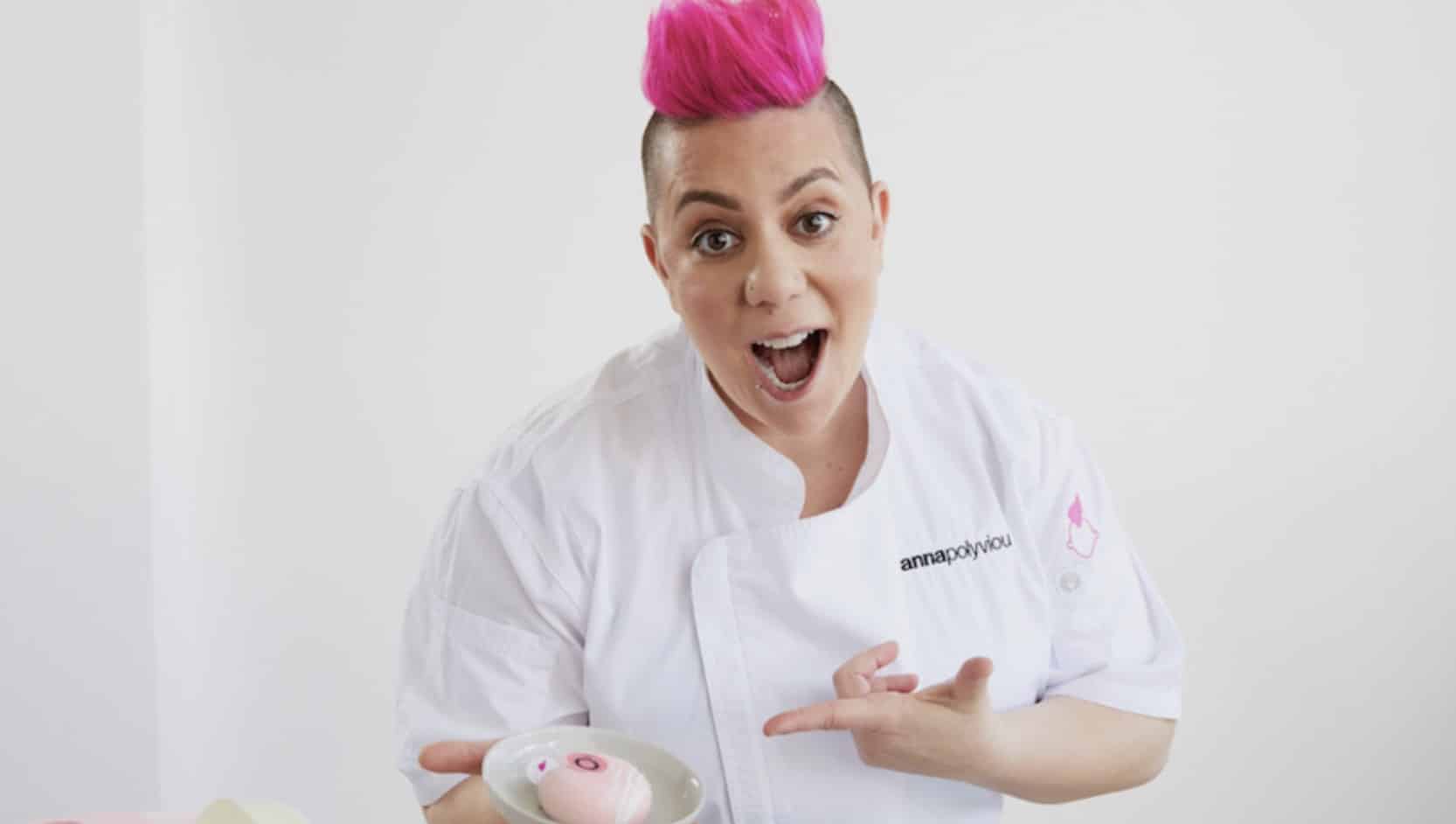 Pink haired chef Anna Polyviou holding a cake