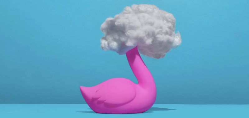 Pink flamingo on blue background with head in clouds